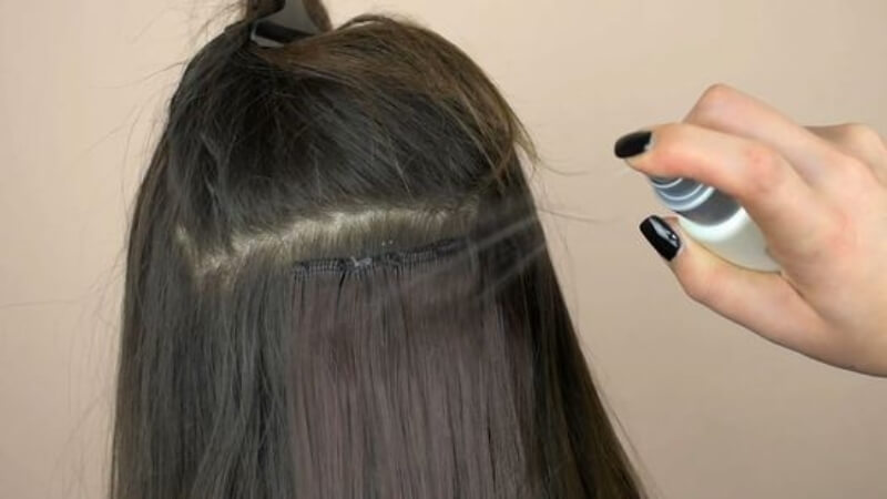 Apply adhesive remover into invisible tape in hair