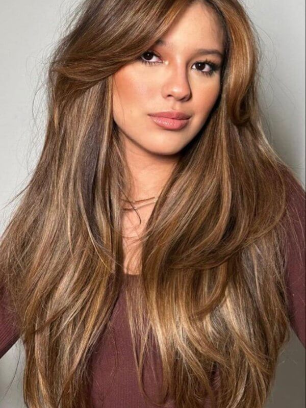 Soft, layered hair with a side part, offering a voluminous and stylish look