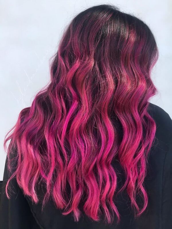 A bold, futuristic look with electric pink and red hair color