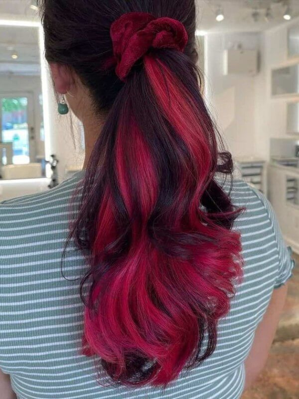 A sleek ponytail with bold streaks of pink and red for extra flair