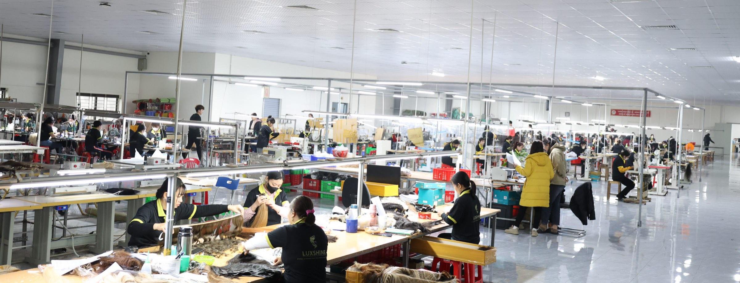 Luxshine workers preparing hair at long tables across the factory floor