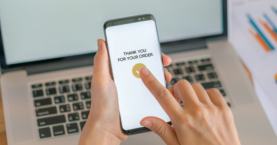 A phone showing an order confirmation in front of a laptop