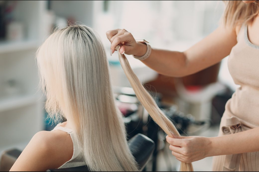 A stylist fitting blonde extensions in a salon