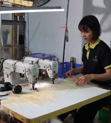 A technician sewing blonde hair wefts at a sewing machine