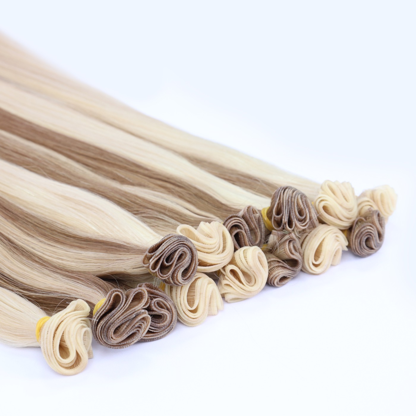 Luxury tier wefts in blonde and brown shades, their tops rolled