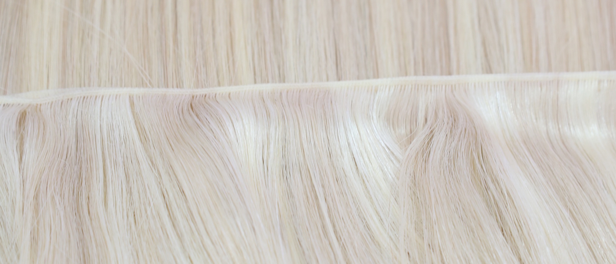 Blonde Vietnamese Remy hair sewn into a weft, seen up close